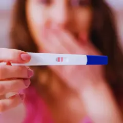 Kobieta trzyma test ciążowy z dwoma kreskami. Zastanawia się, ile wynosi l4 w ciąży i jakie są związane z tym świadczenia.