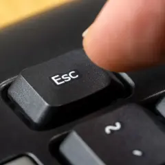 Palec naciska klawisz Esc, symbolizując zakończenie działalności gospodarczej.
