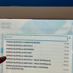 Palec wskazuje na ekranie opcję "PIERWSZA REJESTRACJA SAMOCHODU", szukając informacji o upoważnieniu do rejestracji pojazdu.
