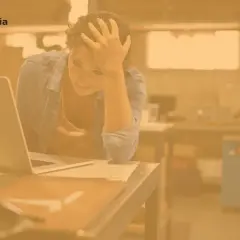 Zrezygnowana kobieta z ręką na czole siedzi przy laptopie. Szuka pracy, ale bezskutecznie.
