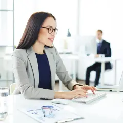 Kobieta w okularach pracuje przy komputerze, przygotowując oświadczenie pracownika dla celów stosowania podwyższonych kosztów uzyskania przychodów.