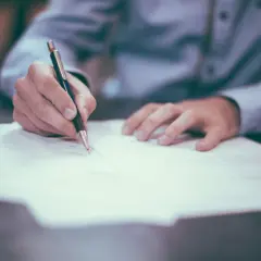 Dłoń pisze na papierze, zastanawiając się, co grozi za porzucenie pracy.