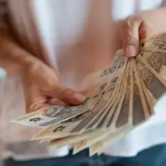 Dłonie trzymają wachlarz banknotów 200 zł. To nagroda za długoletni jubileusz w pracy.