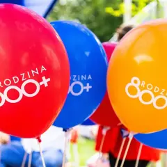 Kolorowe balony z napisem "RODZINA 800+". Radosna atmosfera wsparcia dla rodzin.