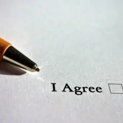 Długopis zbliża się do pola wyboru "I Agree", symbolizując akceptację warunków, np. w kontekście ozusowania umów zleceń.