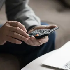 Mężczyzna liczy kapitał początkowy na kalkulatorze, przygotowując wzór ZUS.