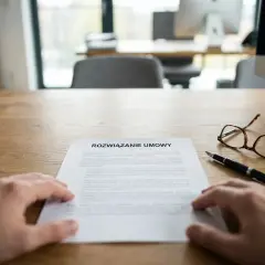 Dłoń nad dokumentem "Rozwiązanie umowy". Obok pióro i okulary. Czas na formalne odstąpienie od umowy.