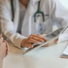 Lekarz wyjaśnia pacjentowi, jak obliczyć wynagrodzenie chorobowe, korzystając z tabletu.