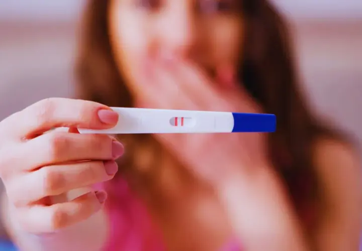 Kobieta trzyma test ciążowy z dwoma kreskami. Zastanawia się, ile wynosi l4 w ciąży i jakie są związane z tym świadczenia.