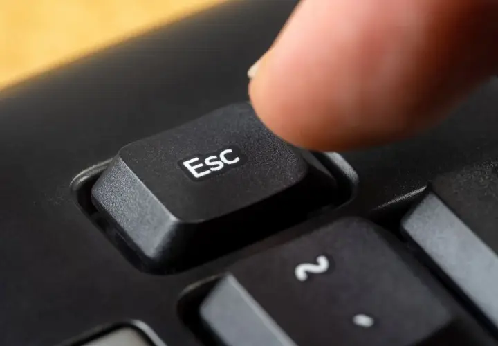 Palec naciska klawisz Esc, symbolizując zakończenie działalności gospodarczej.