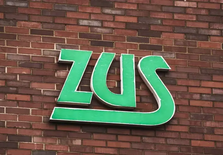 Zielone litery ZUS na ceglanej ścianie. Zastanawiasz się, jak długo jeszcze będziesz czekać na odpowiedź z ZUS?