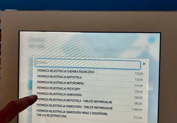 Palec wskazuje na ekranie opcję "PIERWSZA REJESTRACJA SAMOCHODU", szukając informacji o upoważnieniu do rejestracji pojazdu.