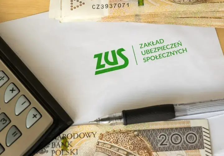 Kalkulator, długopis i pieniądze leżą obok koperty z logo ZUS. Temat: dziedziczenie składek ZUS.