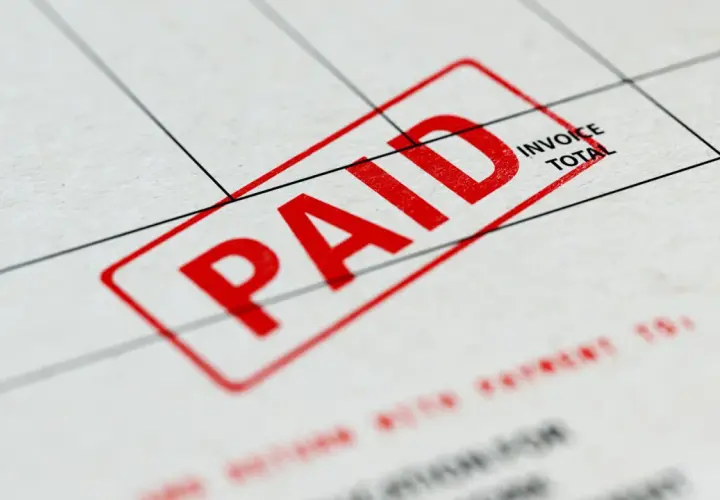 Czerwony stempel "PAID" na dokumencie, który może być fakturą zaliczkową a VAT.