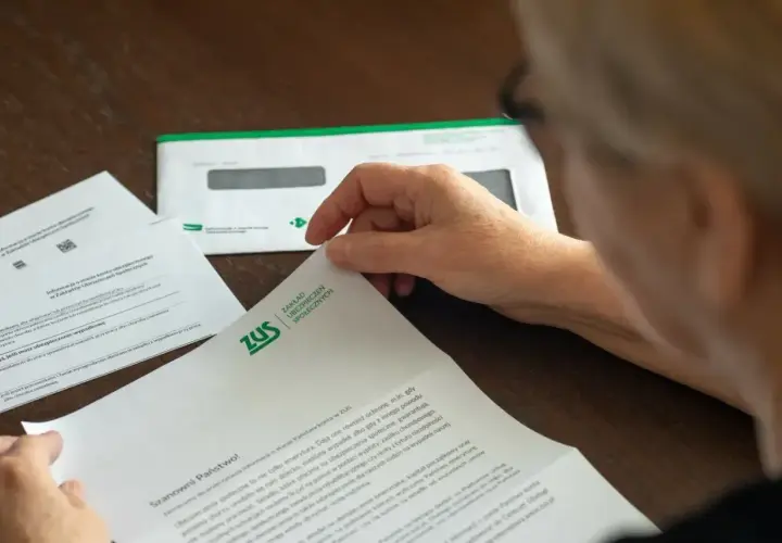 Osoba przegląda dokument ZUS. Może to być informacja o zwrocie nadpłaty lub inne pismo z ubezpieczalni.