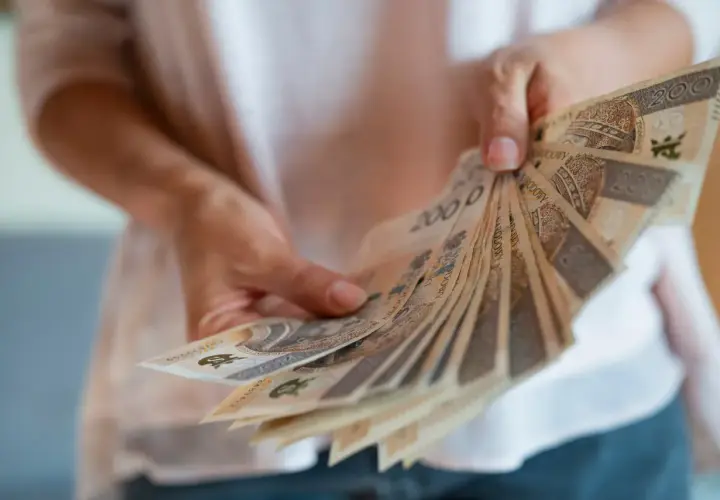 Dłonie trzymają wachlarz banknotów 200 zł. To nagroda za długoletni jubileusz w pracy.