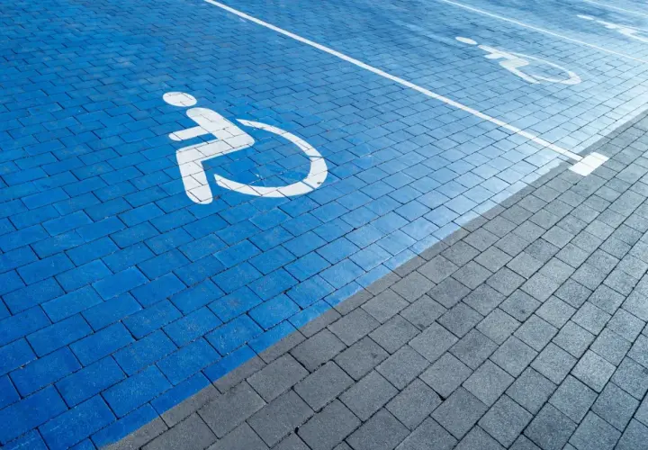Niebieski parking dla osób z niepełnosprawnościami. Orzeczenie o niepełnosprawności można dostać na wiele chorób, np. ruchowych, wzroku, słuchu.