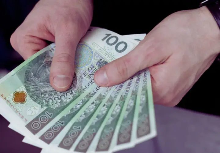 Dłonie trzymające kilka banknotów 100 zł.