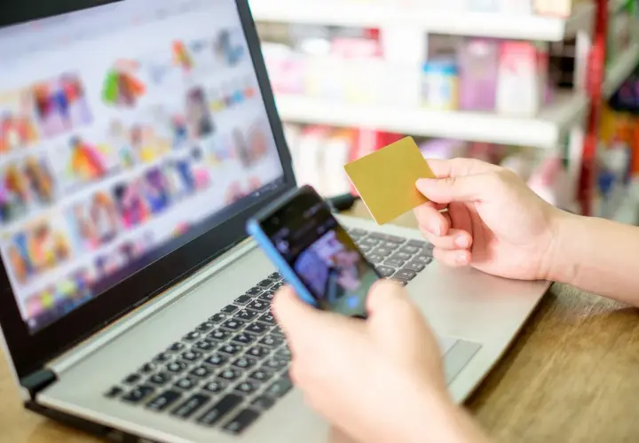 Osoba trzyma kartę płatniczą i telefon, przeglądając zakupy online. Rozważasz odstąpienie od umowy zawartej na odległość?