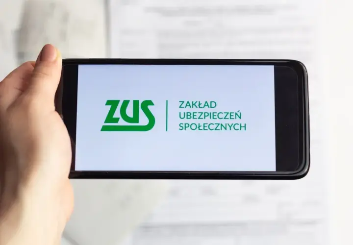 Dłoń trzyma smartfon z logo ZUS. Możliwe, że sprawdzasz zwrot składki zdrowotnej.
