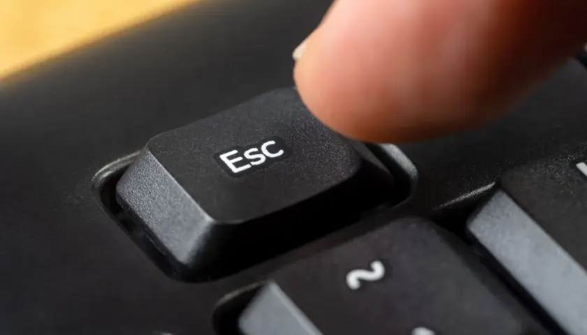 Palec naciska klawisz Esc, symbolizując zakończenie działalności gospodarczej.