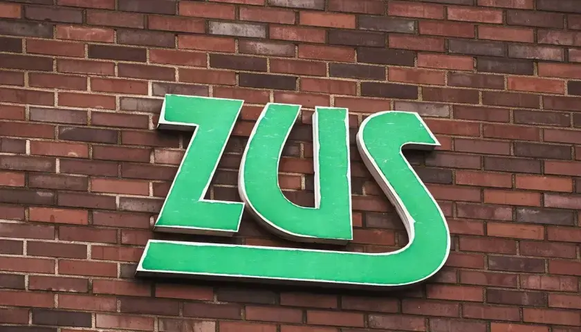 Zielone litery ZUS na ceglanej ścianie. Zastanawiasz się, jak długo jeszcze będziesz czekać na odpowiedź z ZUS?