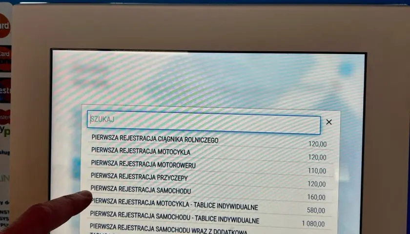 Palec wskazuje na ekranie opcję "PIERWSZA REJESTRACJA SAMOCHODU", szukając informacji o upoważnieniu do rejestracji pojazdu.