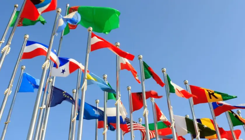Wiele flag powiewa na wietrze na tle błękitnego nieba. Czy to symboliczne przedstawienie krajów, które oferują raj podatkowy?