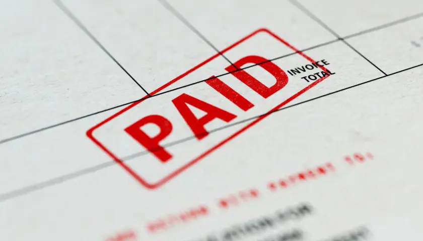 Czerwony stempel "PAID" na dokumencie, który może być fakturą zaliczkową a VAT.