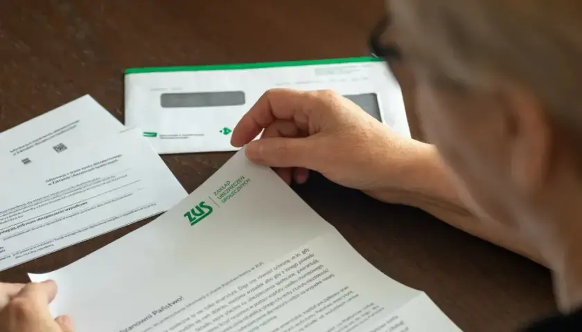 Osoba przegląda dokument ZUS. Może to być informacja o zwrocie nadpłaty lub inne pismo z ubezpieczalni.