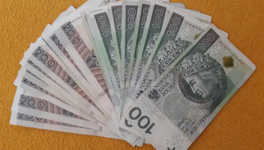 Stos banknotów 100 i 200 zł, gotowy na darowiznę dla dziecka.