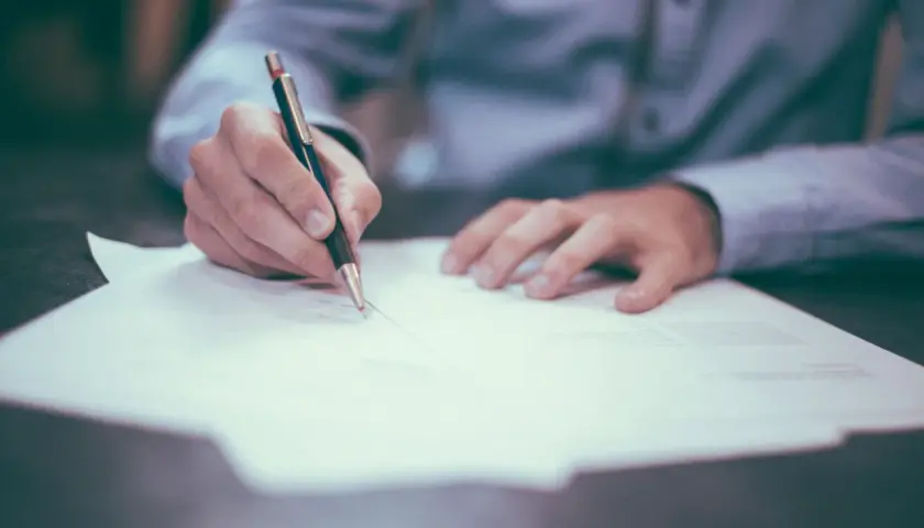 Dłoń pisze na papierze, zastanawiając się, co grozi za porzucenie pracy.