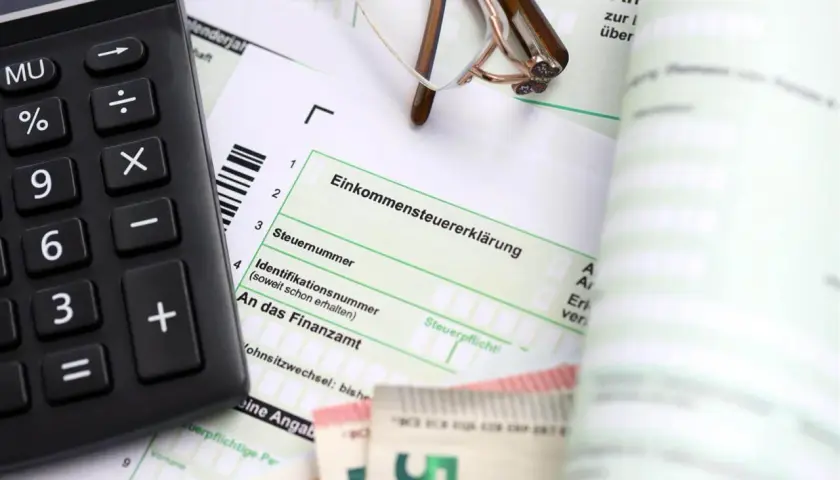Kalkulator, okulary i dokumenty podatkowe, które mogą pomóc w ustaleniu daty powstania obowiązku podatkowego.