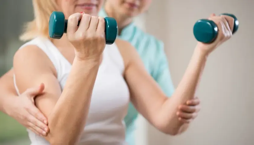 Rehabilitacja z hantlami. Po świadczeniu rehabilitacyjnym można dowiedzieć się, ile wynosi renta.