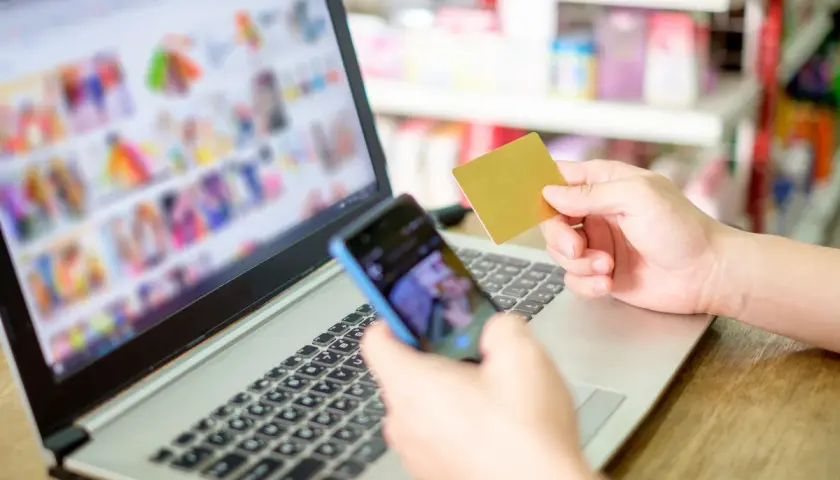 Osoba trzyma kartę płatniczą i telefon, przeglądając zakupy online. Rozważasz odstąpienie od umowy zawartej na odległość?