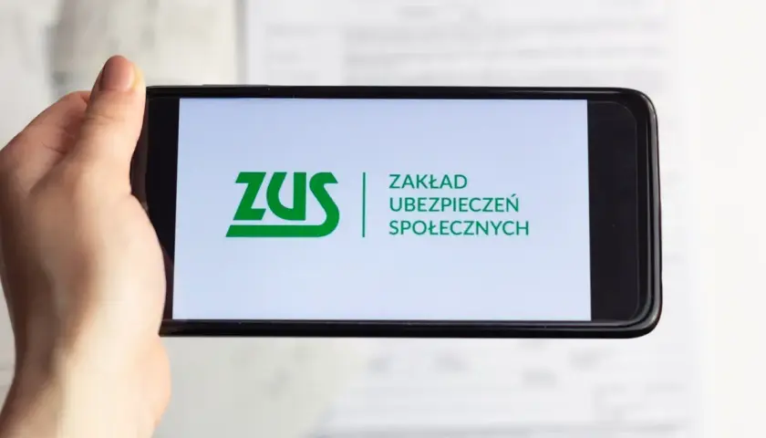 Dłoń trzyma smartfon z logo ZUS. Możliwe, że sprawdzasz zwrot składki zdrowotnej.