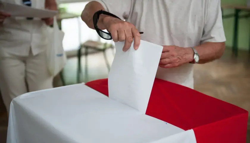 Mężczyzna wrzuca kartę do urny. Dowiedz się, jak głosować poza miejscem zamieszkania, aby Twój głos się liczył.