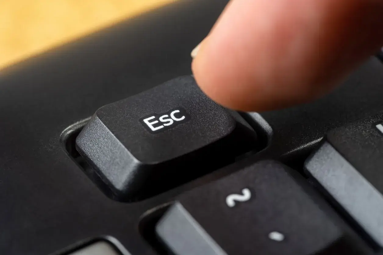 Palec naciska klawisz Esc, symbolizując zakończenie działalności gospodarczej.