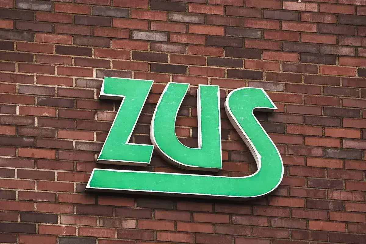 Zielone litery ZUS na ceglanej ścianie. Zastanawiasz się, jak długo jeszcze będziesz czekać na odpowiedź z ZUS?
