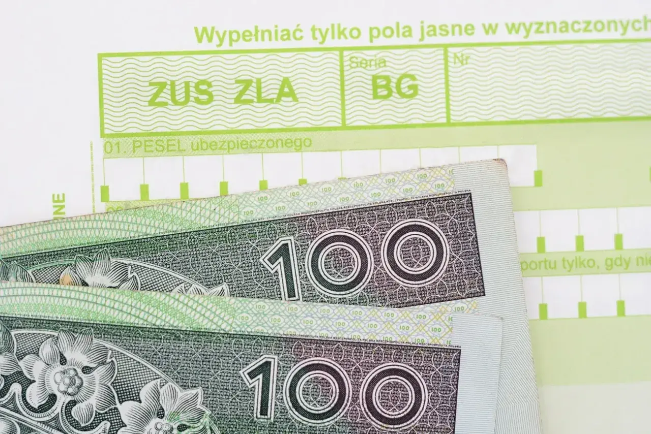 Formularz ZUS ZLA i banknoty 100 zł. Pytanie: ile wynosi zasiłek chorobowy?