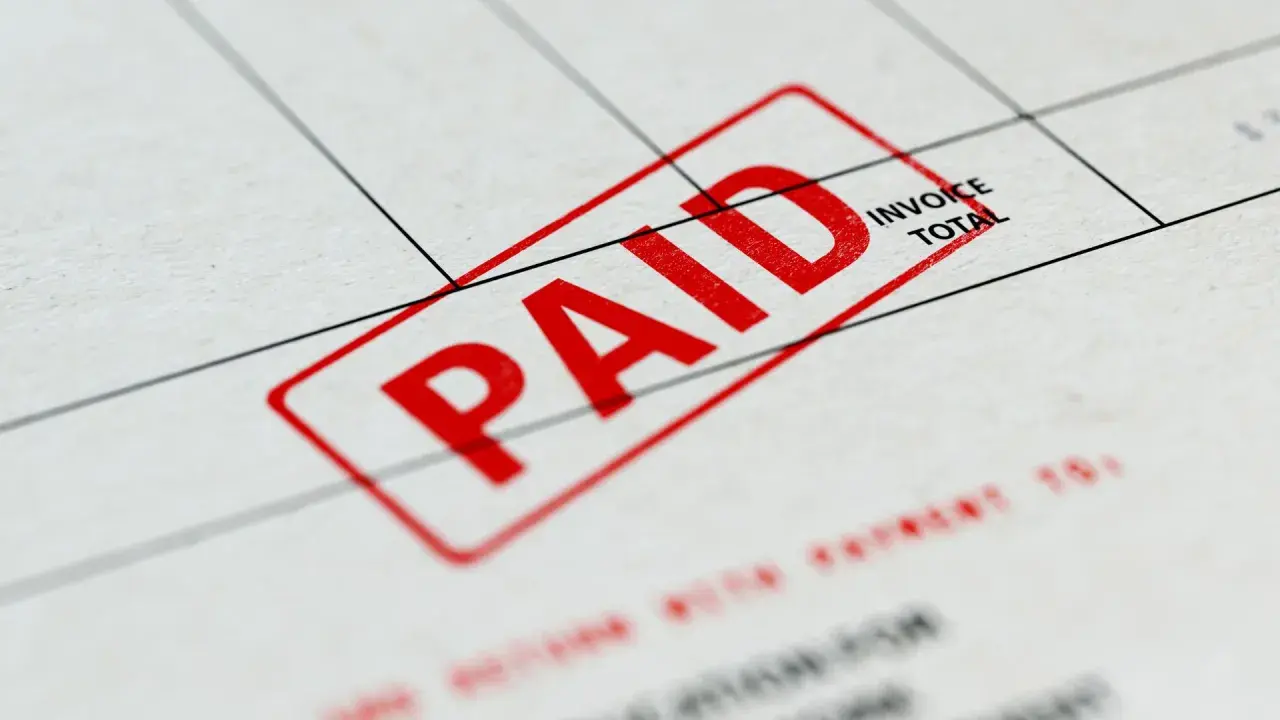 Czerwony stempel "PAID" na dokumencie, który może być fakturą zaliczkową a VAT.