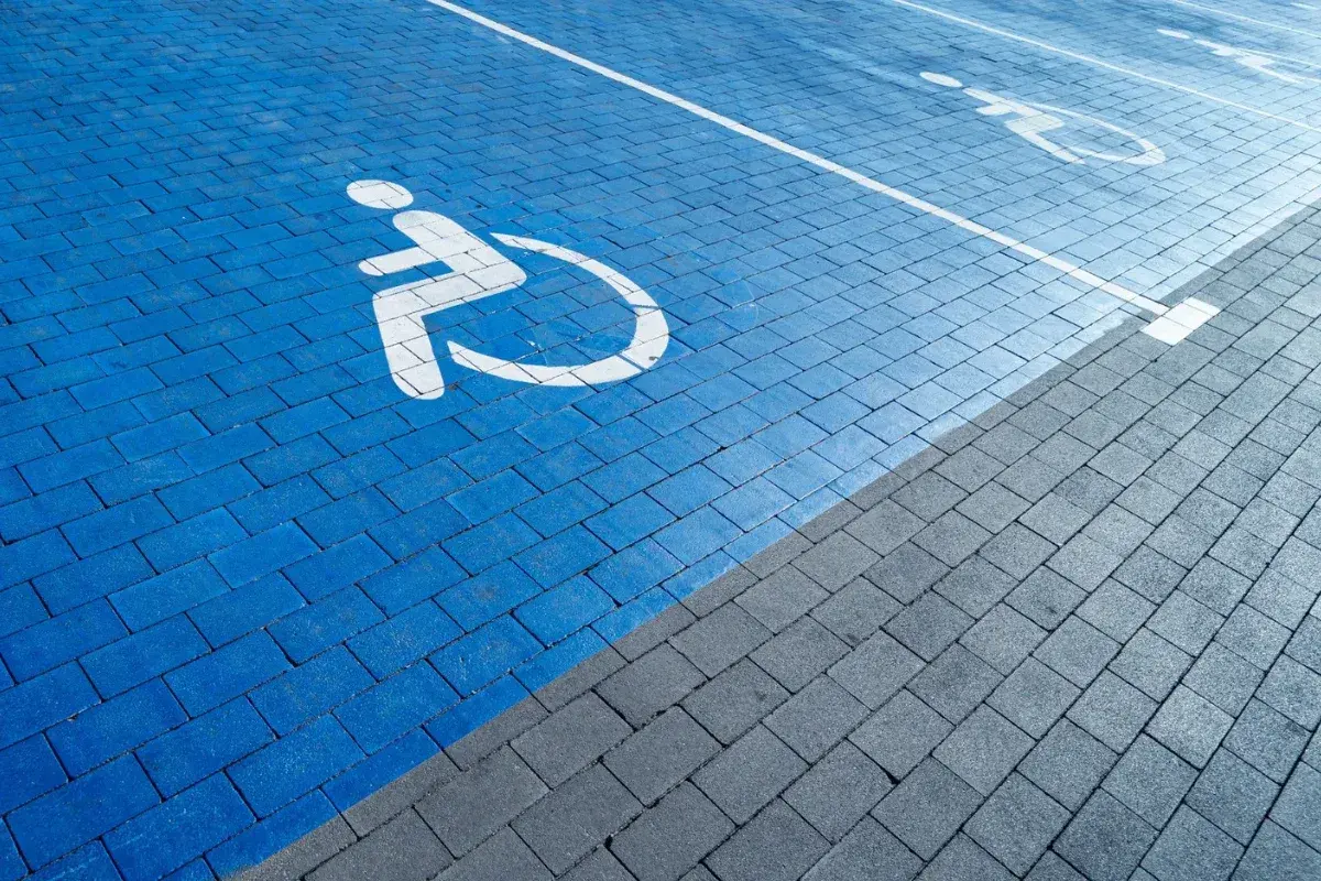 Niebieski parking dla osób z niepełnosprawnościami. Orzeczenie o niepełnosprawności można dostać na wiele chorób, np. ruchowych, wzroku, słuchu.