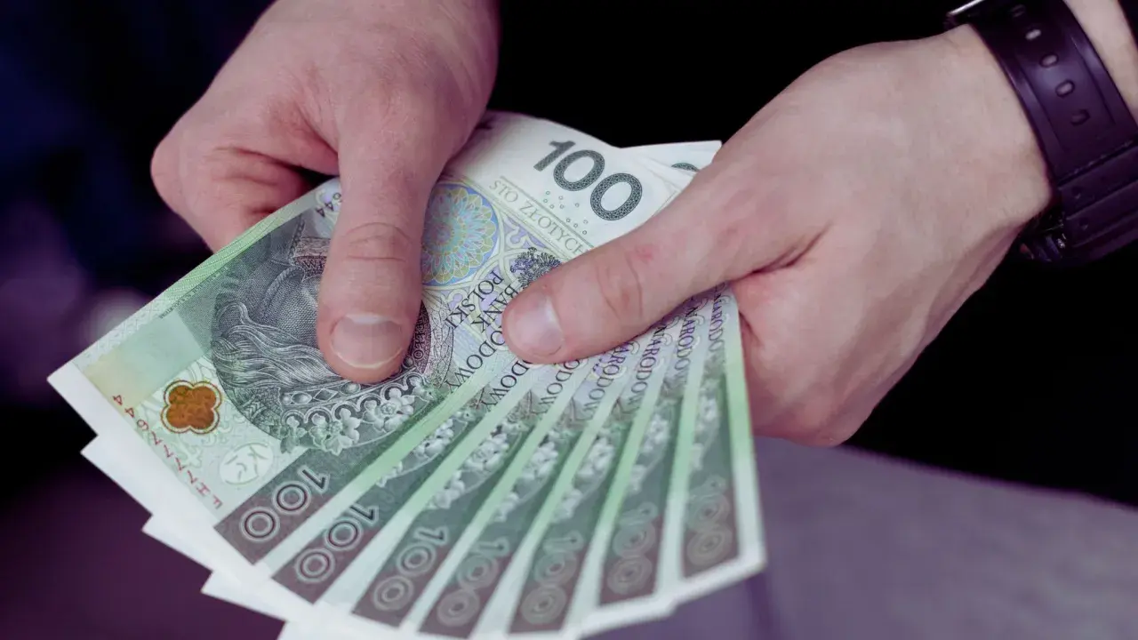 Dłonie trzymające kilka banknotów 100 zł.