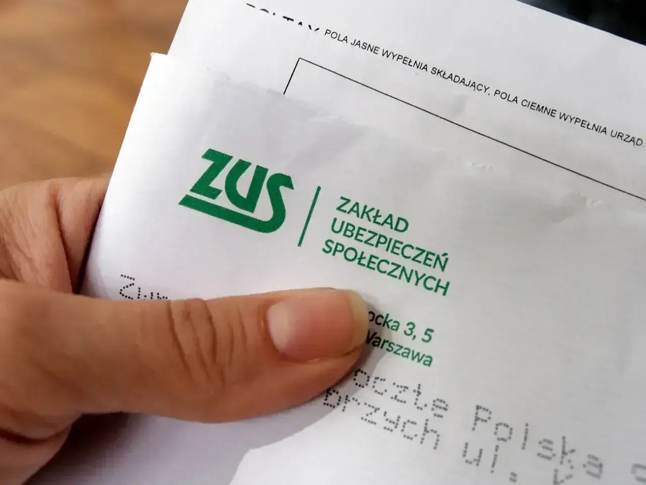 Dłoń trzyma dokument ZUS. Warto sprawdzić, ile wynosi odprawa emerytalna, by mieć pewność co do przyszłości.