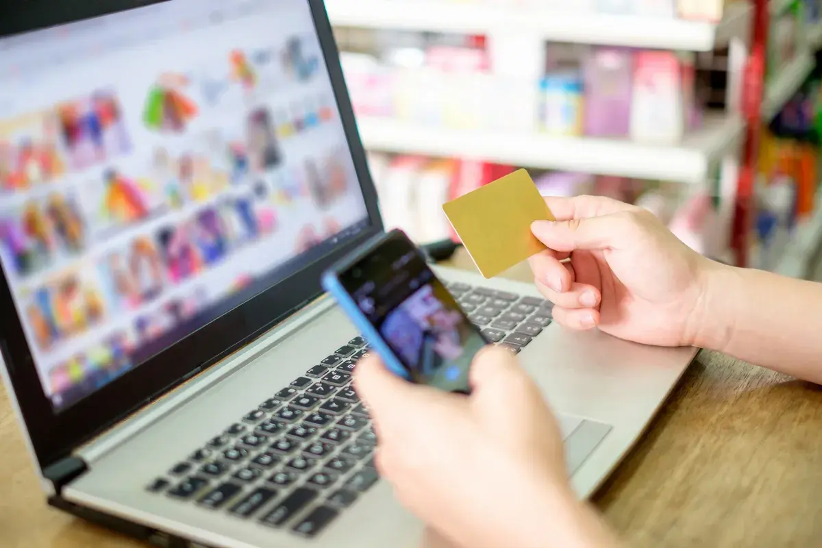 Osoba trzyma kartę płatniczą i telefon, przeglądając zakupy online. Rozważasz odstąpienie od umowy zawartej na odległość?