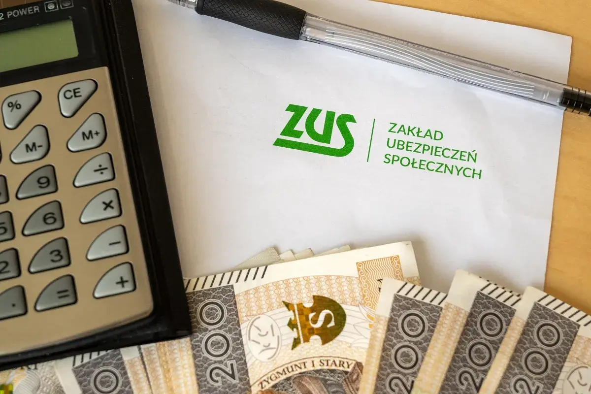 Kalkulator, długopis, dokument ZUS i polskie banknoty. Obrazek sugeruje rozważania: l4 na umowa zlecenie ile płatne?
