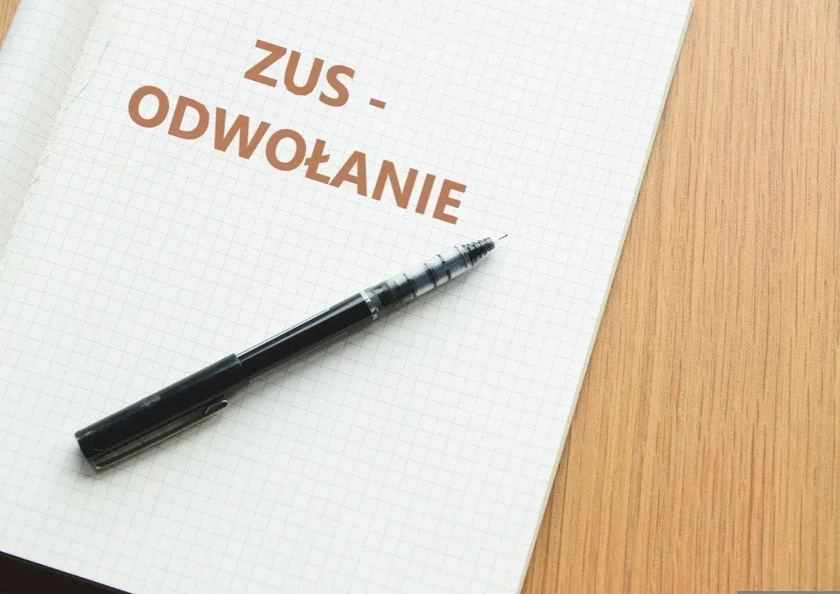 Notatnik z napisem "ZUS - ODWOŁANIE" i długopisem. Dowiedz się, jak napisać odwołanie od decyzji ZUS.