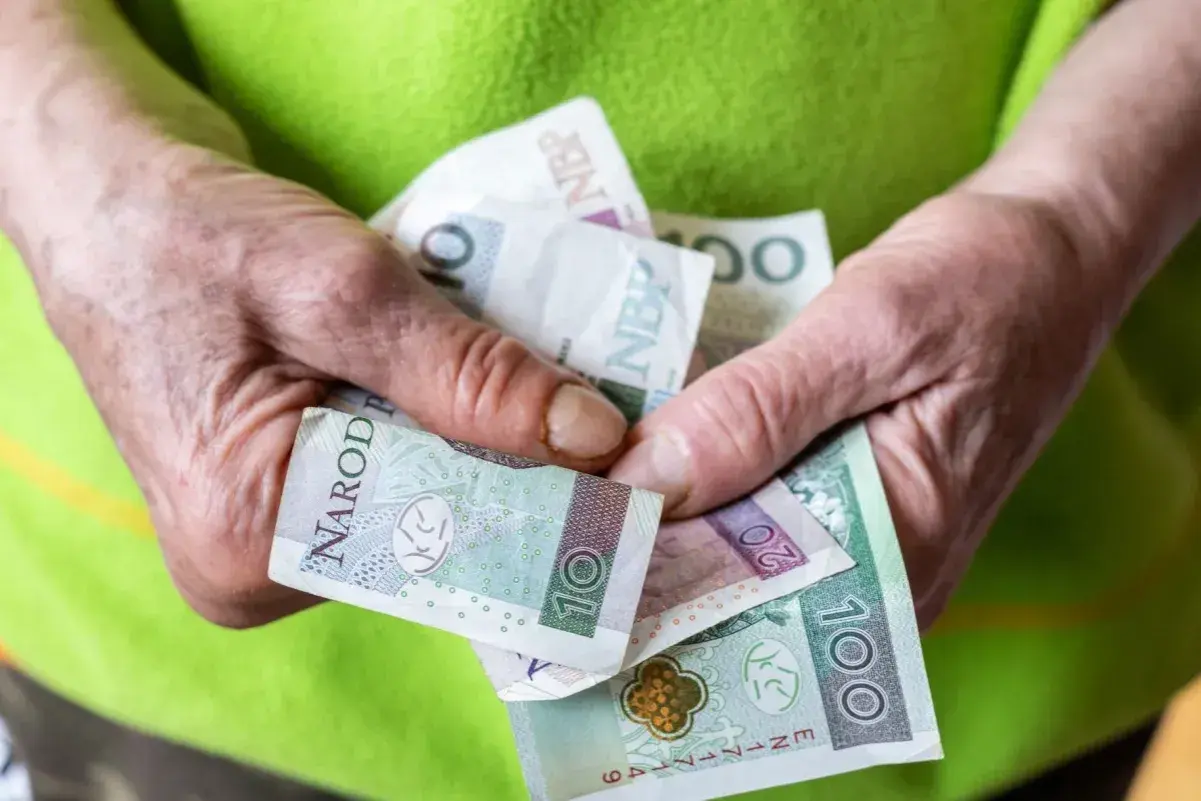 Dłonie trzymają polskie banknoty. Pytanie: czy można pracować na rencie z całkowitą niezdolnością do pracy?