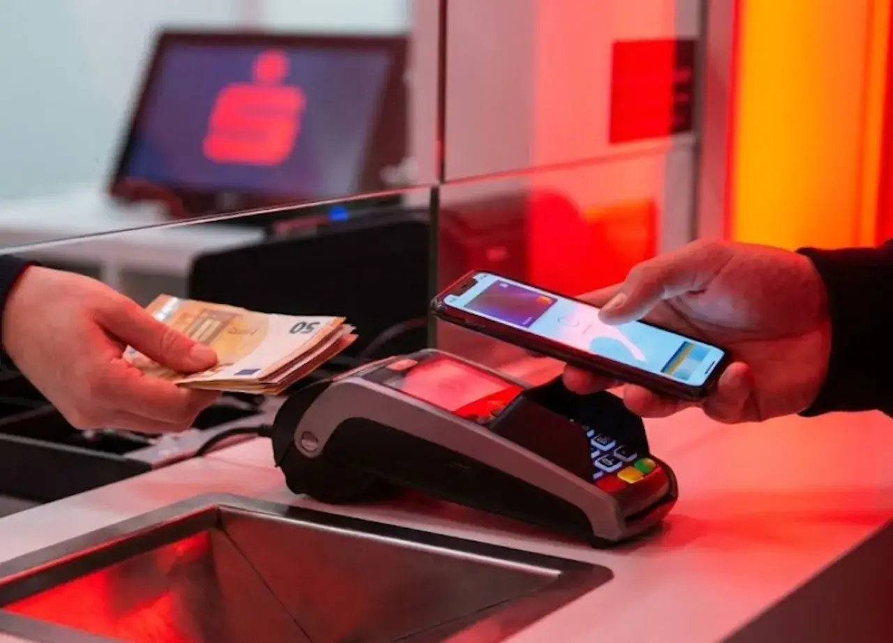 Płatność zbliżeniowa telefonem przy terminalu. Gotówka w ręce, zbliża się limit płatności gotówką.