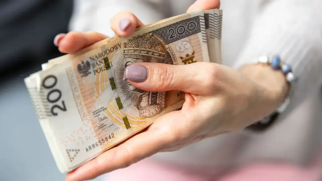 Dłonie trzymające plik banknotów 200 zł. Pytanie: czy można pracować na rencie z całkowitą niezdolnością do pracy?